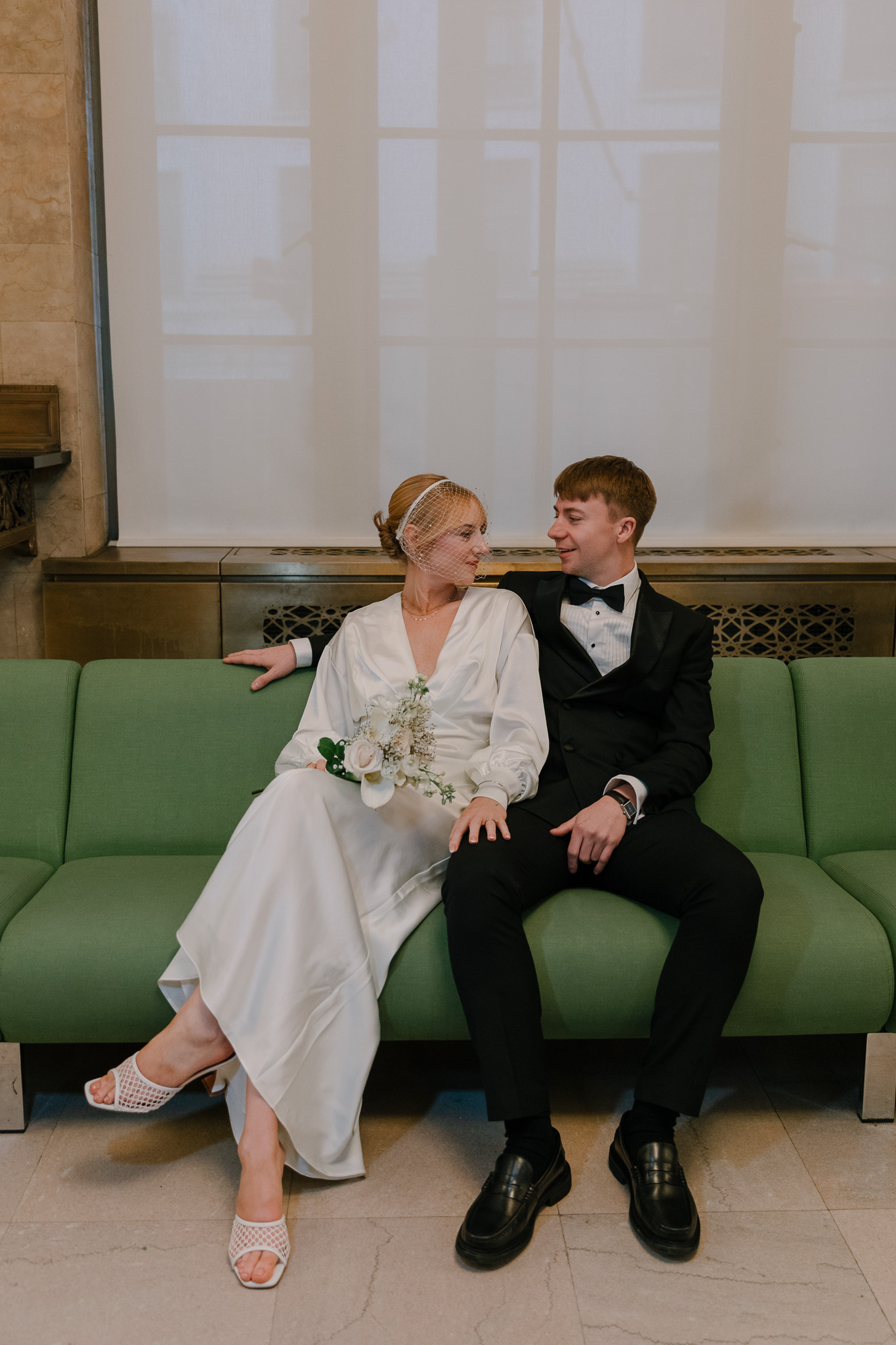 bride and groom sitting together on a green couch at new york city clerk office